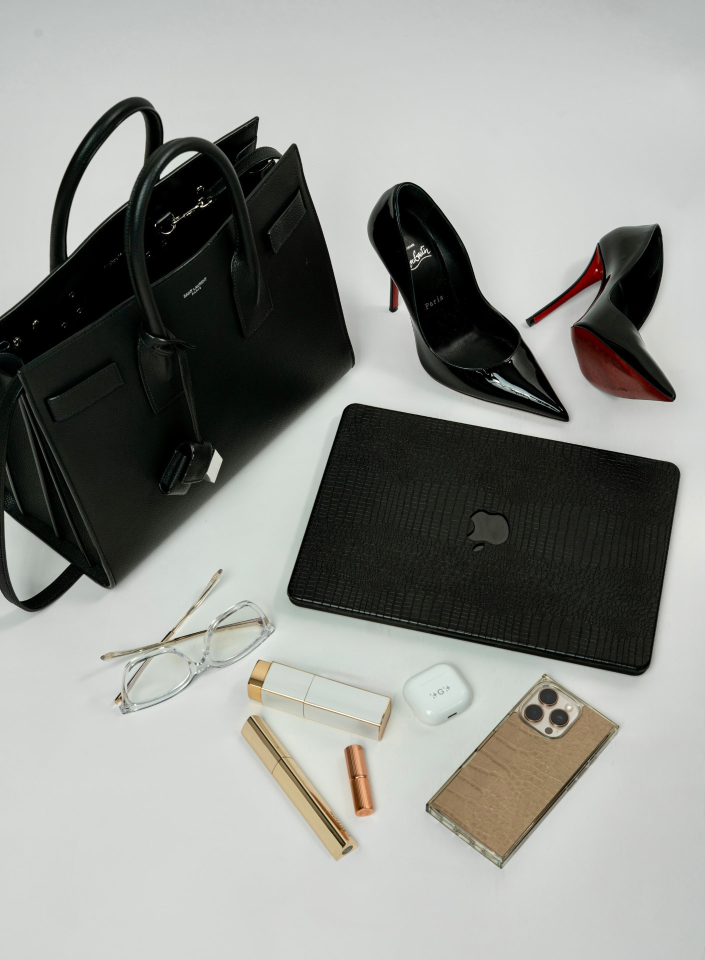 Flatlay of Gina's off-the-clock essentials: black handbag, heels, laptop, and accessories