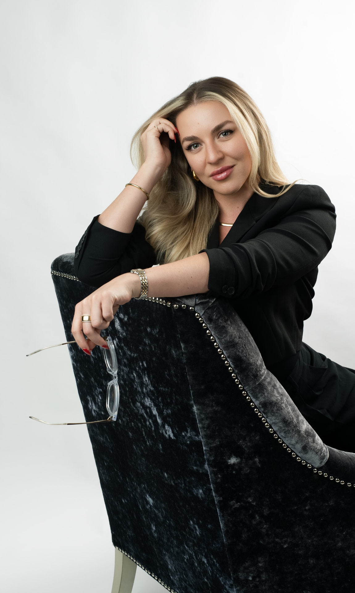 Gina De La Guardia seated in a velvet chair against a dark backdrop